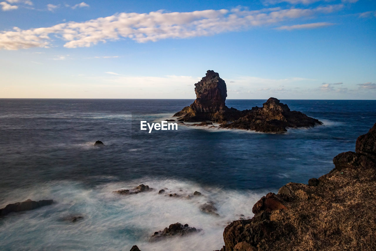 Scenic view of rock formation in sea against sky