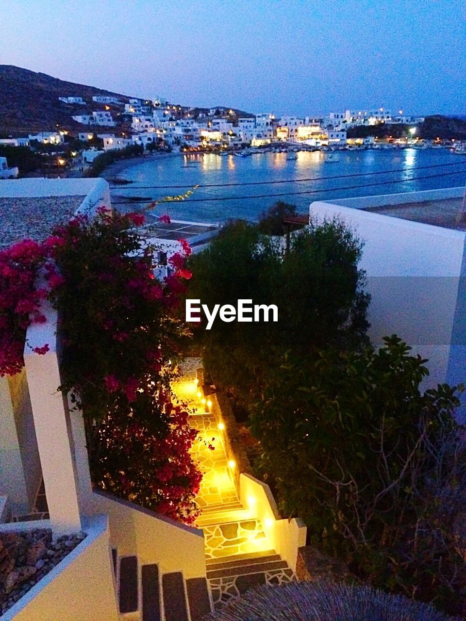 Illuminated cityscape by sea against sky at night