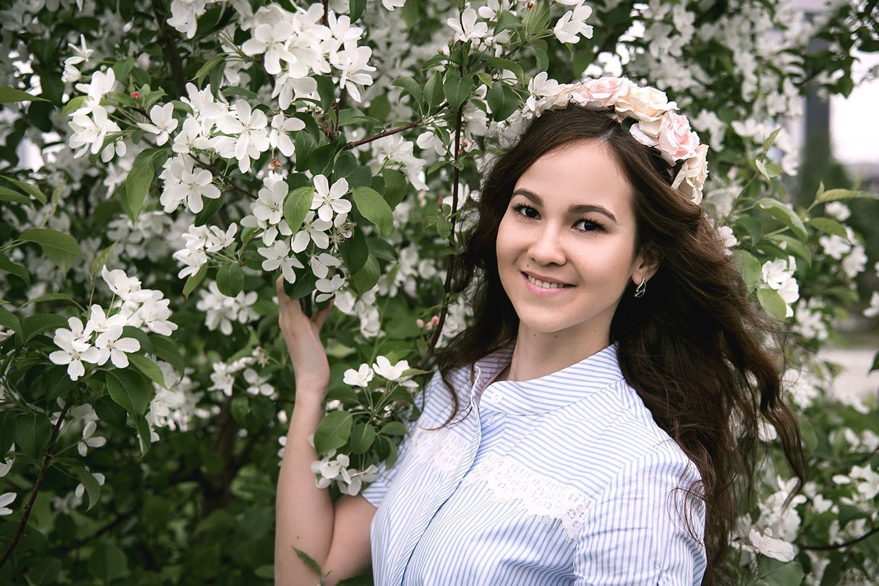 Portrait of beautiful woman wearing flower wreath by tree