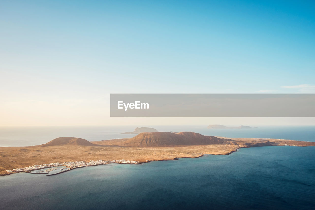 Amazing drone view of volcanic graciosa island washing by blue sea against cloudless sky in spain