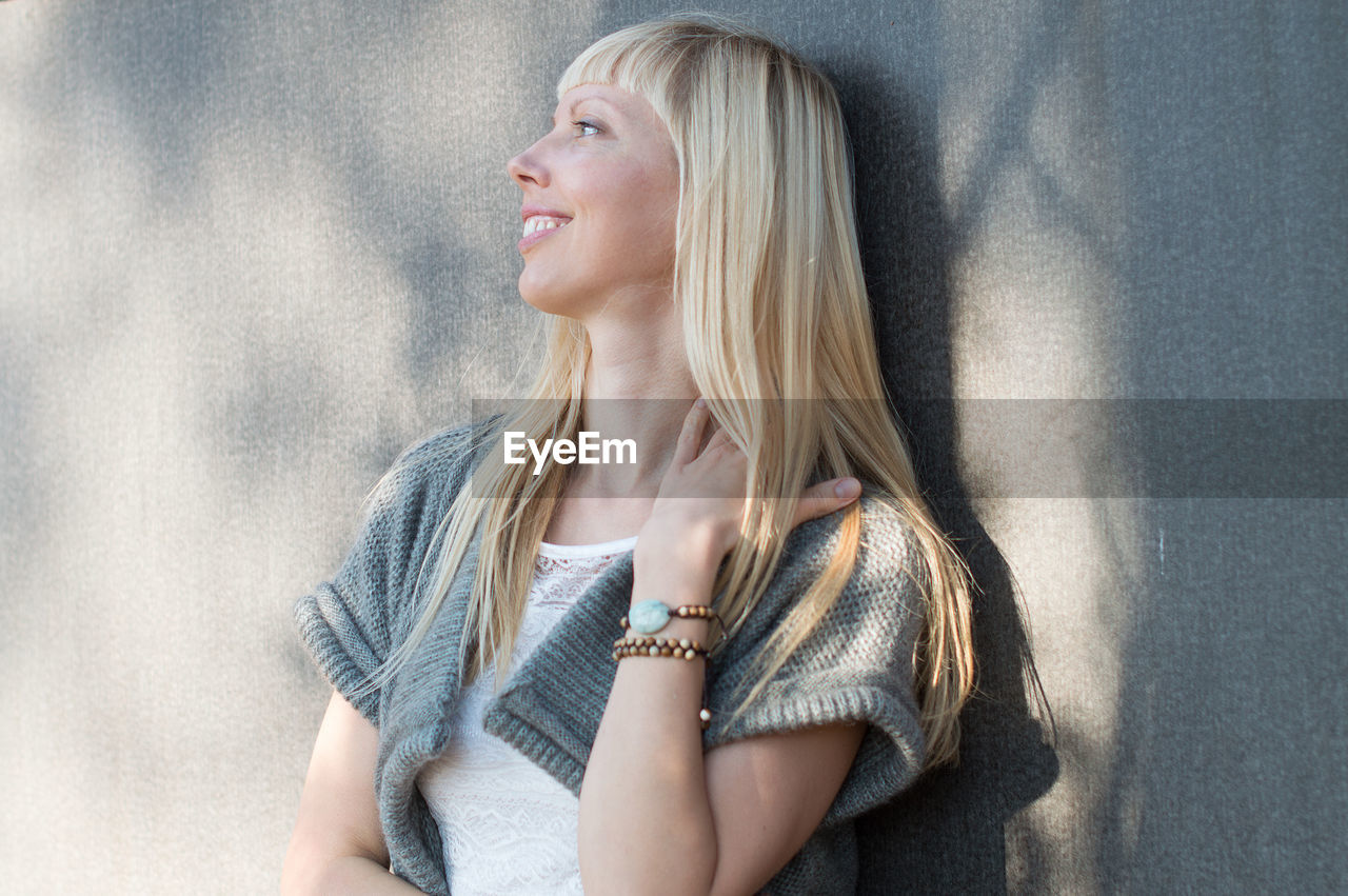 Smiling young woman standing against wall