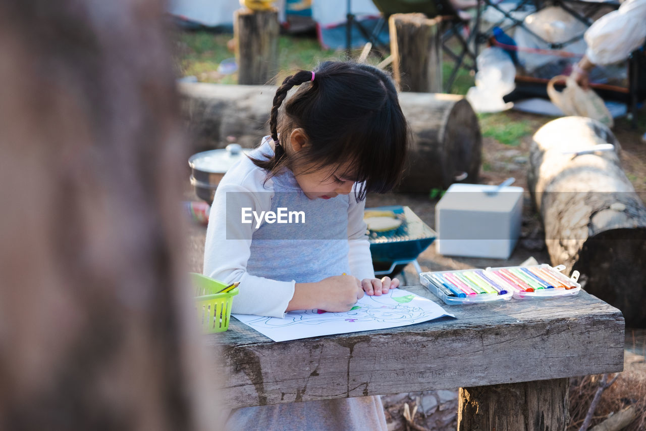 Cute girl drawing on paper outdoors