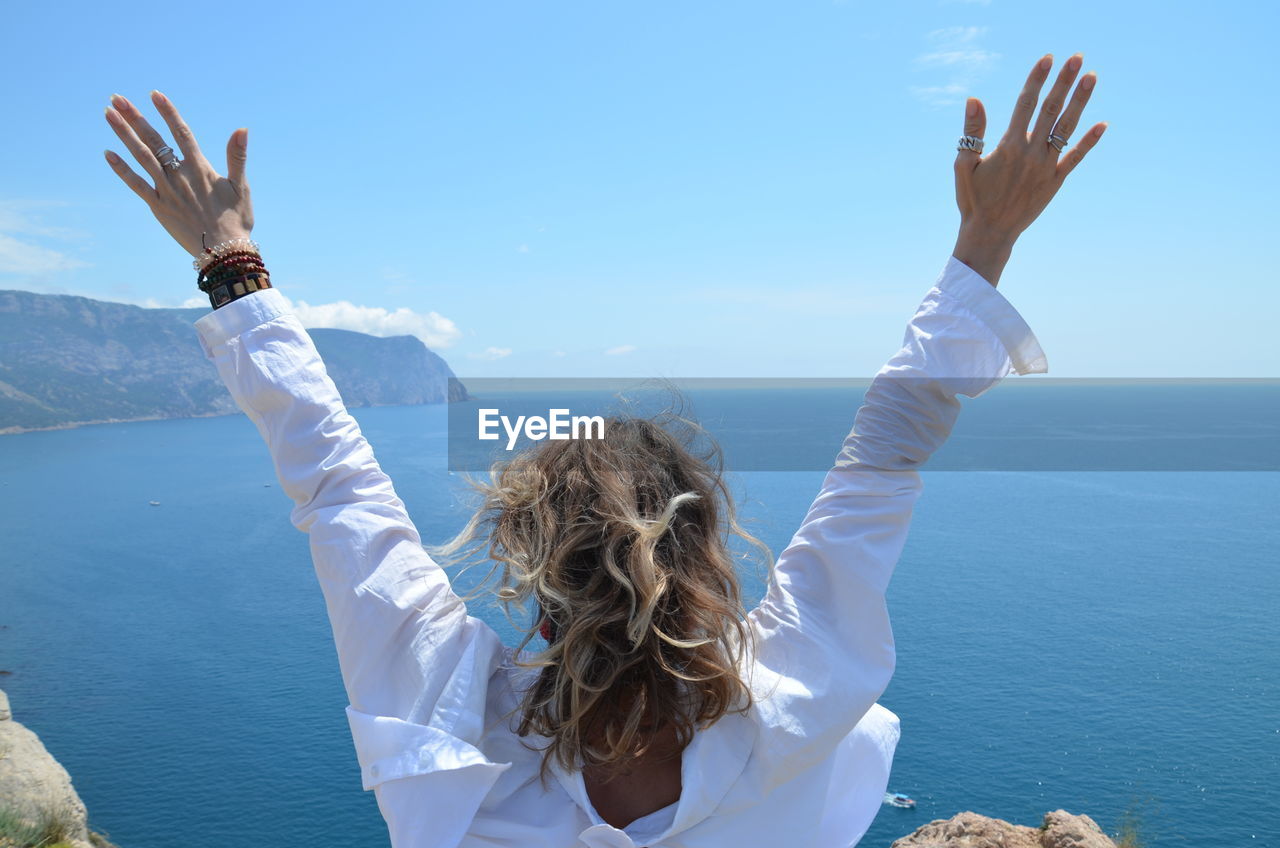 Rear view of woman walking in sea against sky