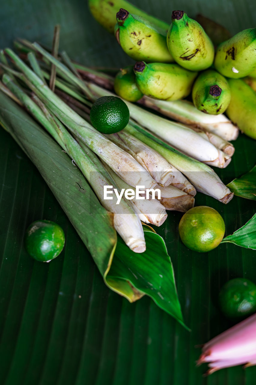 Asian food ingredient with calamansi, lemongrass, tumeric leaves and bananas on a leaf background.