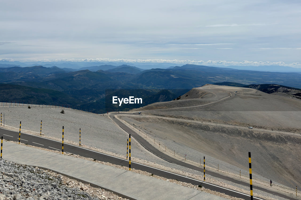 mountain, scenics - nature, environment, landscape, beauty in nature, mountain range, nature, sky, road, transportation, non-urban scene, tranquil scene, day, land, tranquility, cloud, travel, outdoors, high angle view, no people, snow, mountain pass, travel destinations, remote, highway, idyllic, architecture, cold temperature, tourism, valley, sunlight, winter