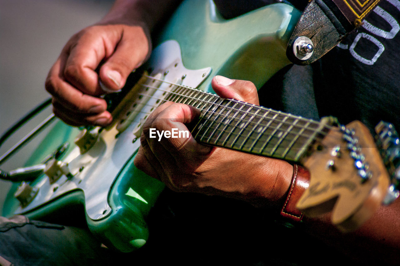 Midsection of street musician playing guitar