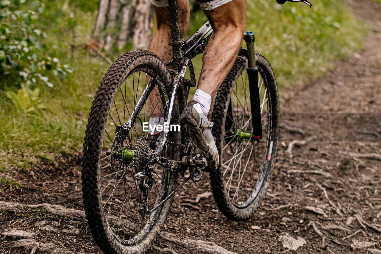 Low section of man riding bicycle on dirt road