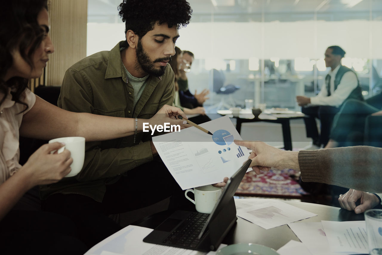 Group of business people analyzing charts during meeting in lobby