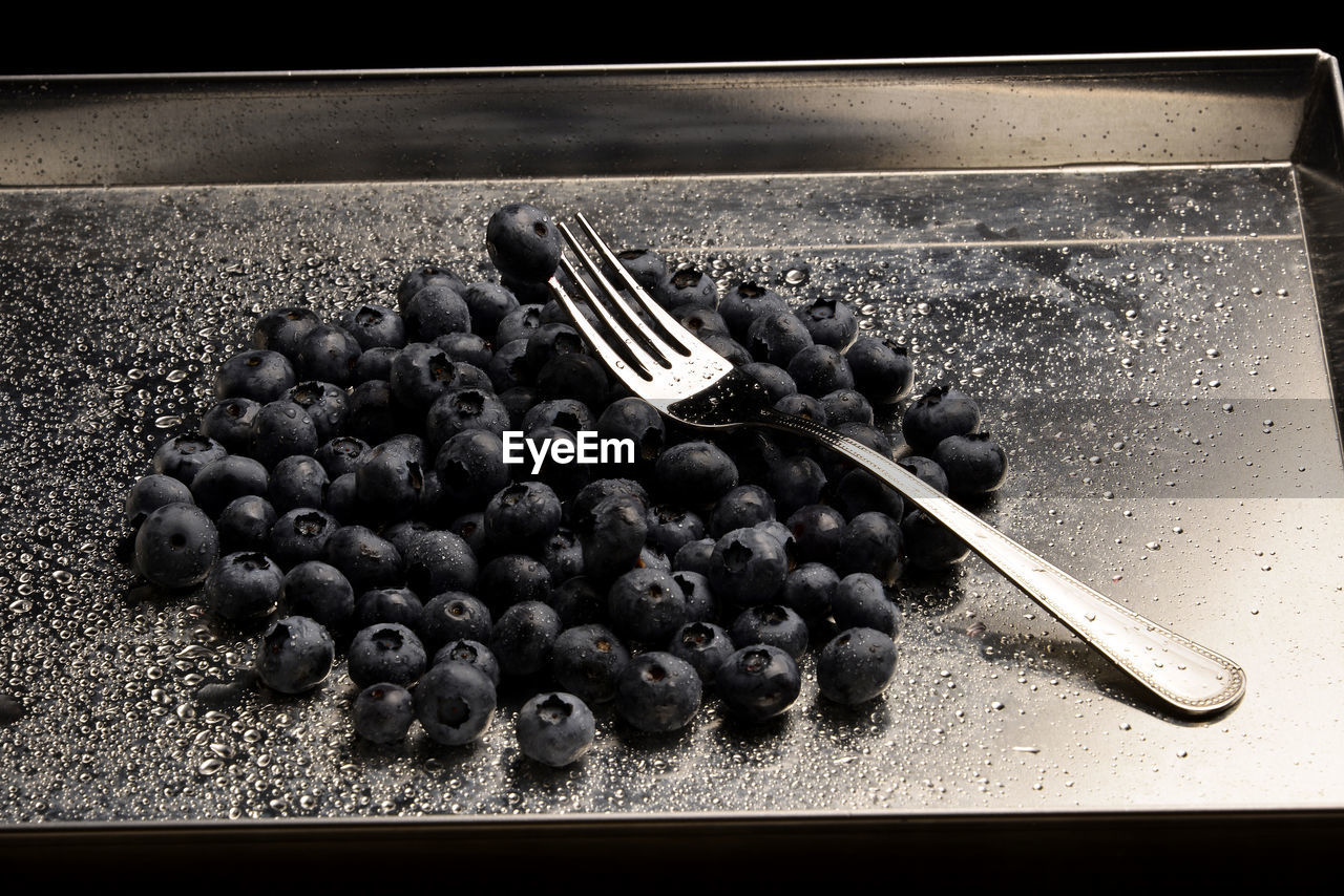 HIGH ANGLE VIEW OF BLUEBERRIES ON METAL TABLE