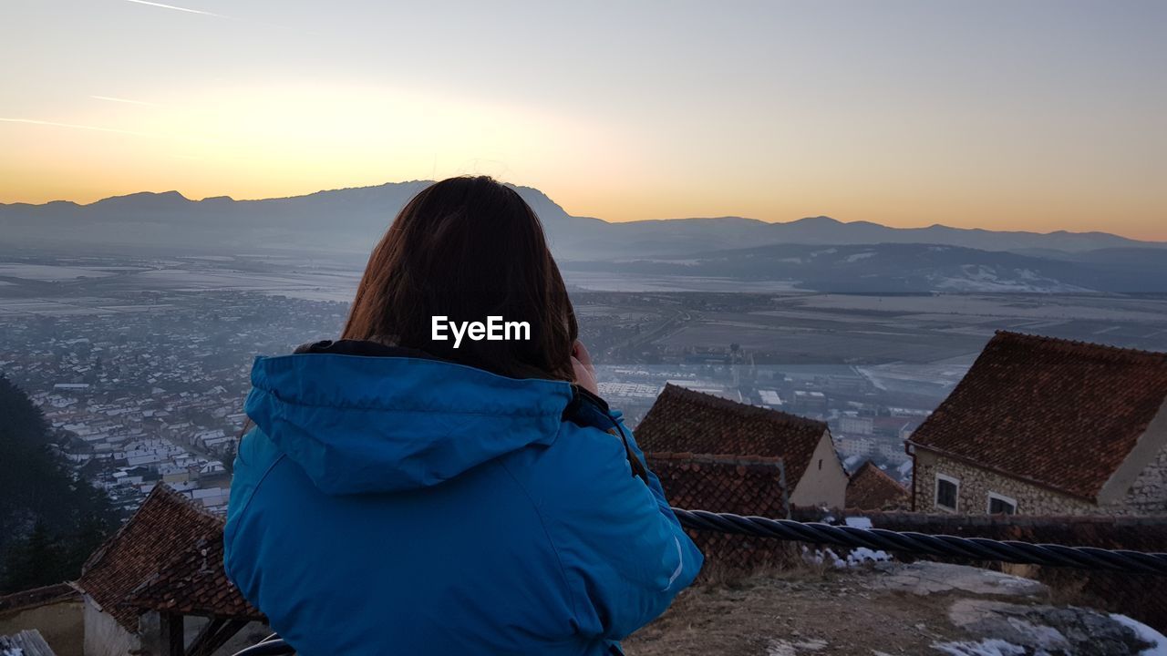 Rear view of woman looking at snowcapped mountains during sunset