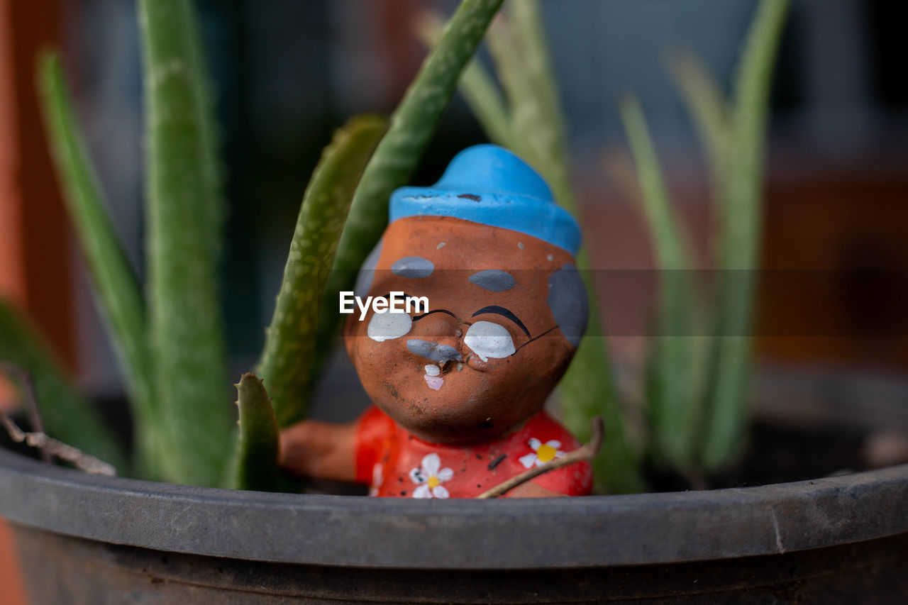 CLOSE-UP OF FIGURINE IN POTTED PLANT
