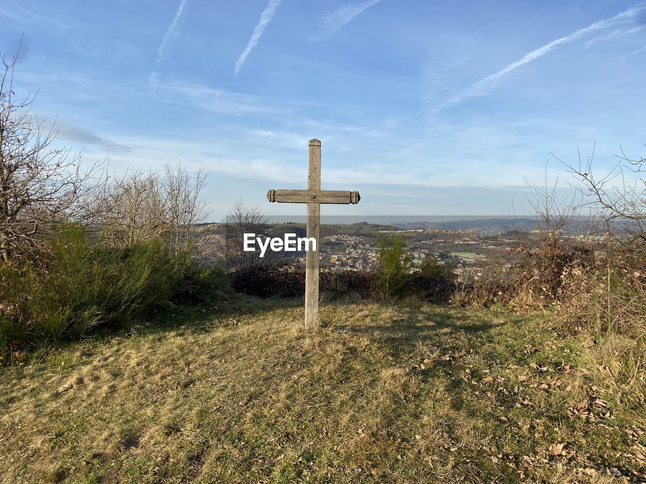 Scenic view of cross in field against blue sky