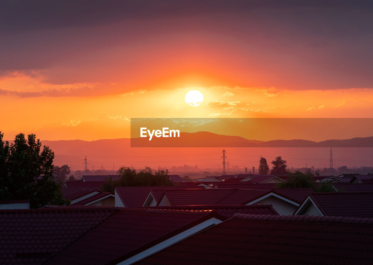 HOUSES AND BUILDINGS AGAINST SKY AT SUNSET