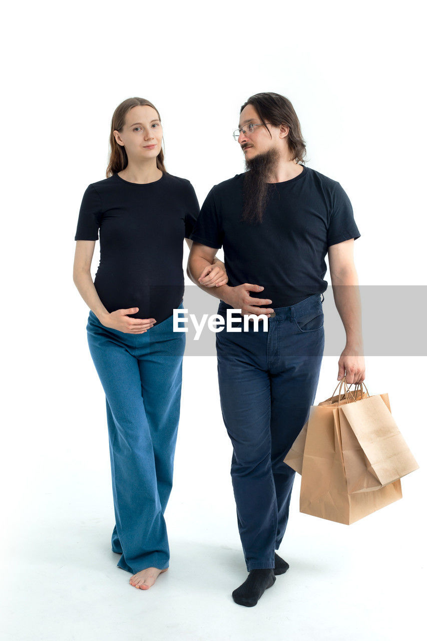 adult, women, two people, full length, white background, studio shot, female, indoors, young adult, casual clothing, cut out, emotion, smiling, happiness, togetherness, standing, clothing, positive emotion, men, bag, portrait, shopping, lifestyles, business, friendship, looking, shopping bag, sleeve, front view, cheerful