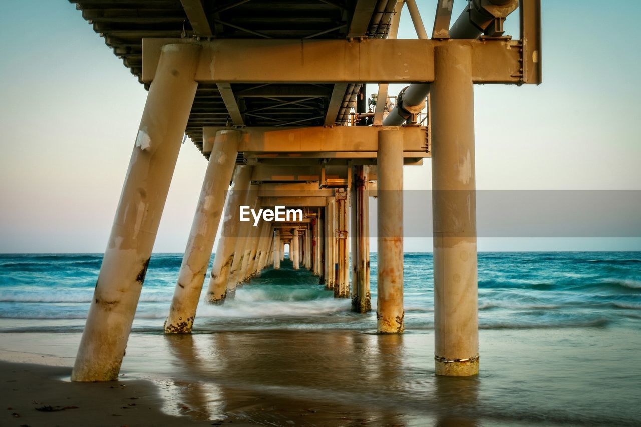 Pier at beach against sky