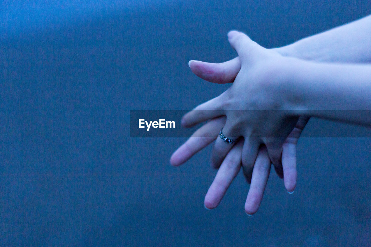 CLOSE-UP OF HAND AGAINST BLUE BACKGROUND
