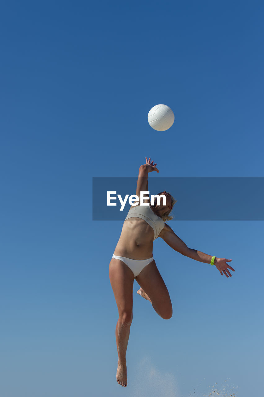 Woman jumping against clear blue sky
