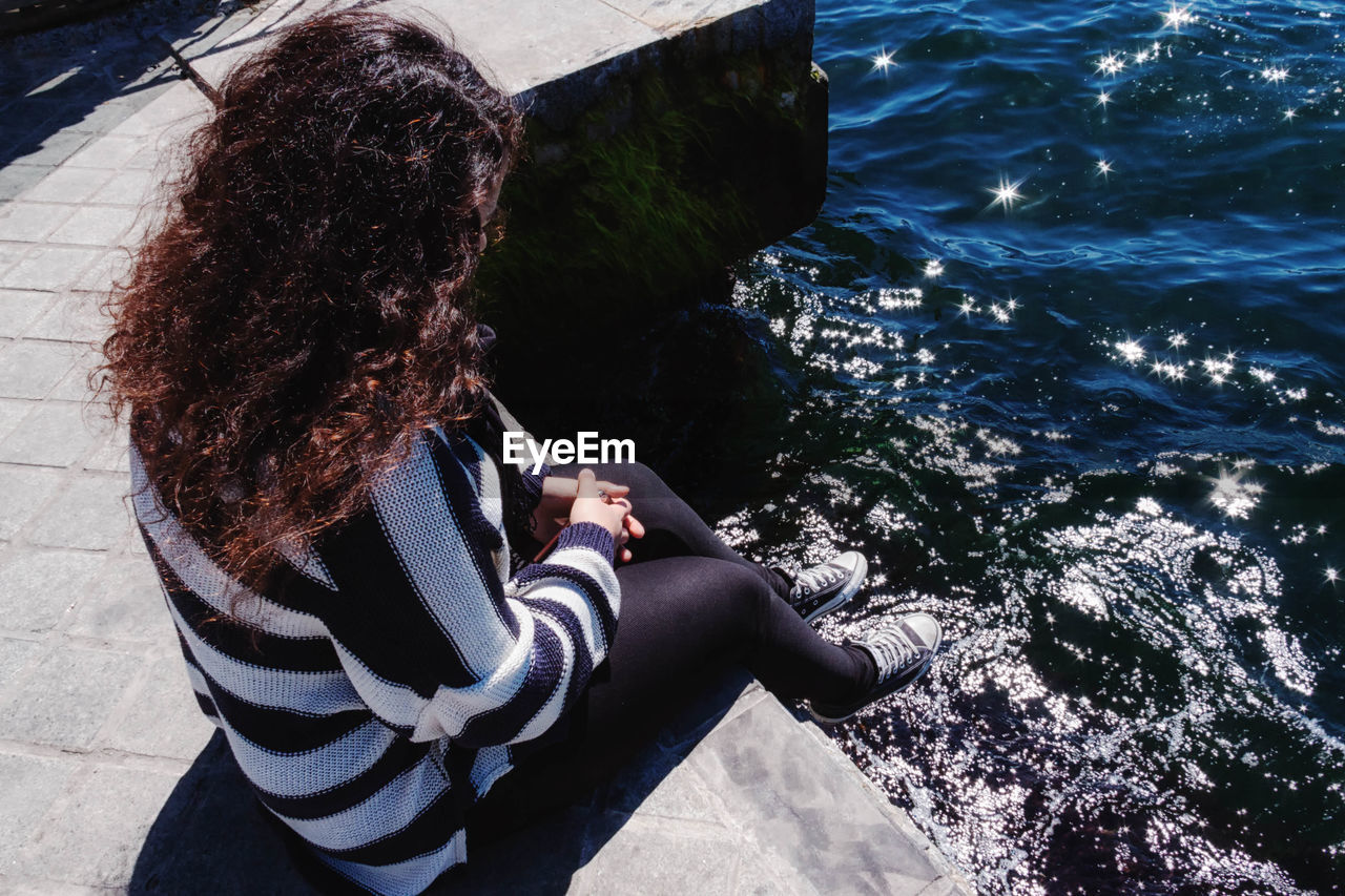 Rear view of woman sitting by sea