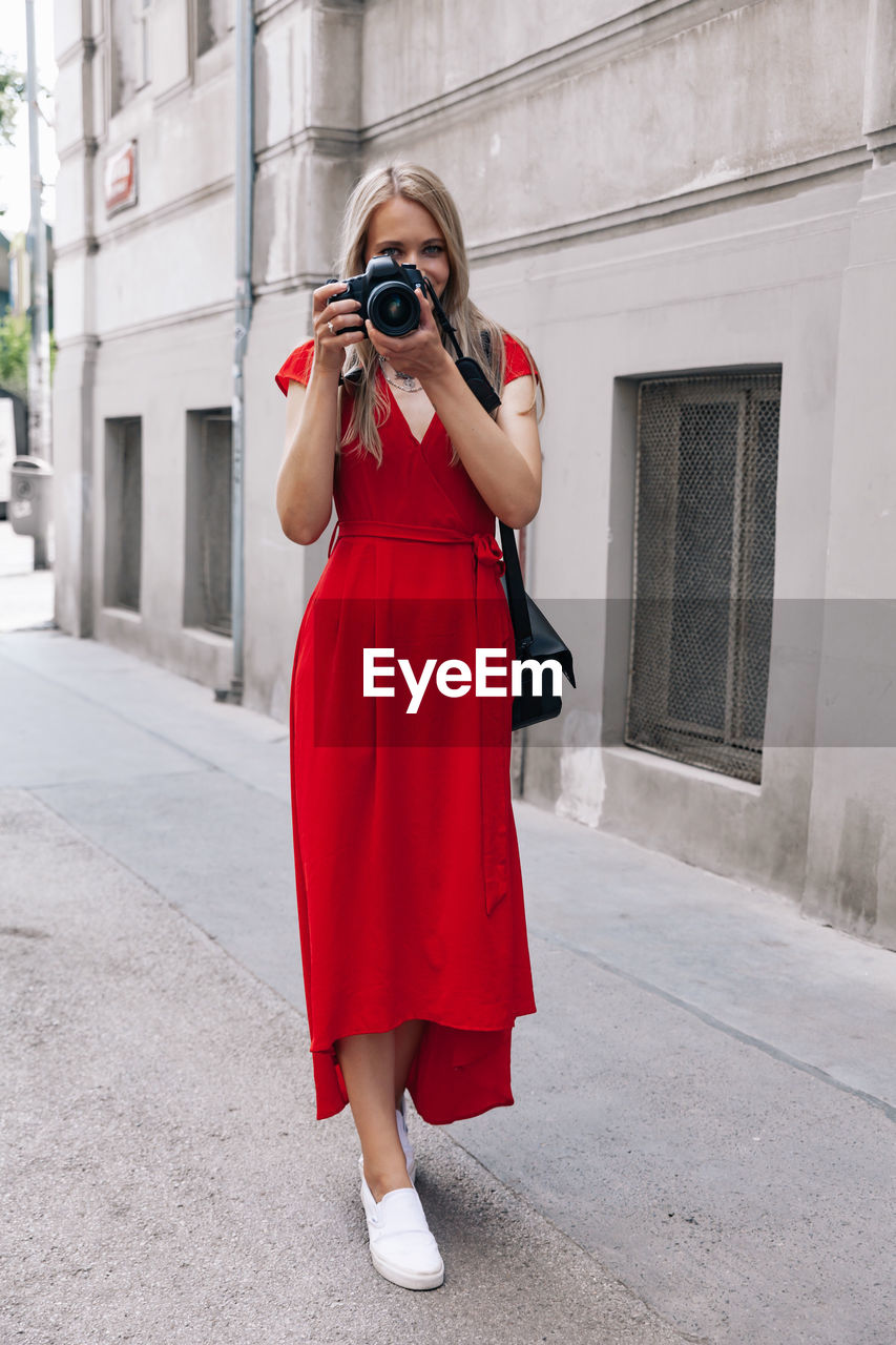 Portrait of woman photographing with camera in city