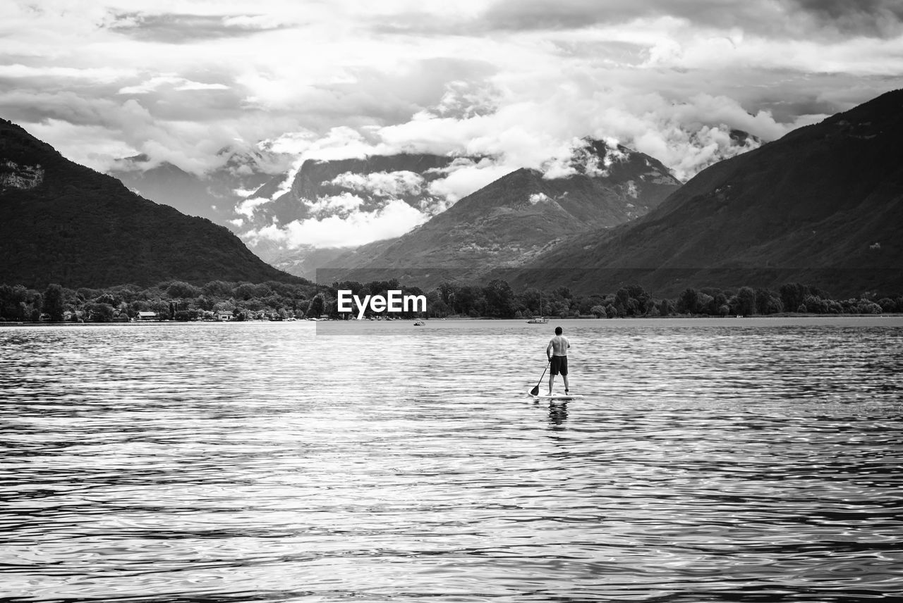 MAN IN LAKE AGAINST MOUNTAINS