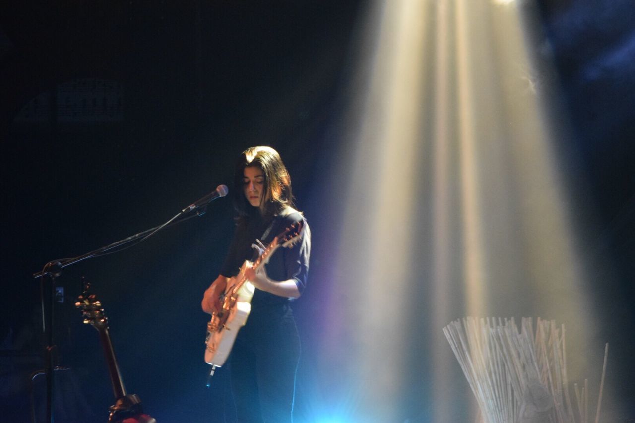 MAN PLAYING GUITAR ON ILLUMINATED STAGE