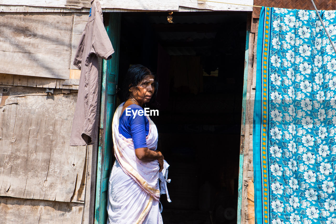 REAR VIEW OF WOMAN STANDING ON BUILDING