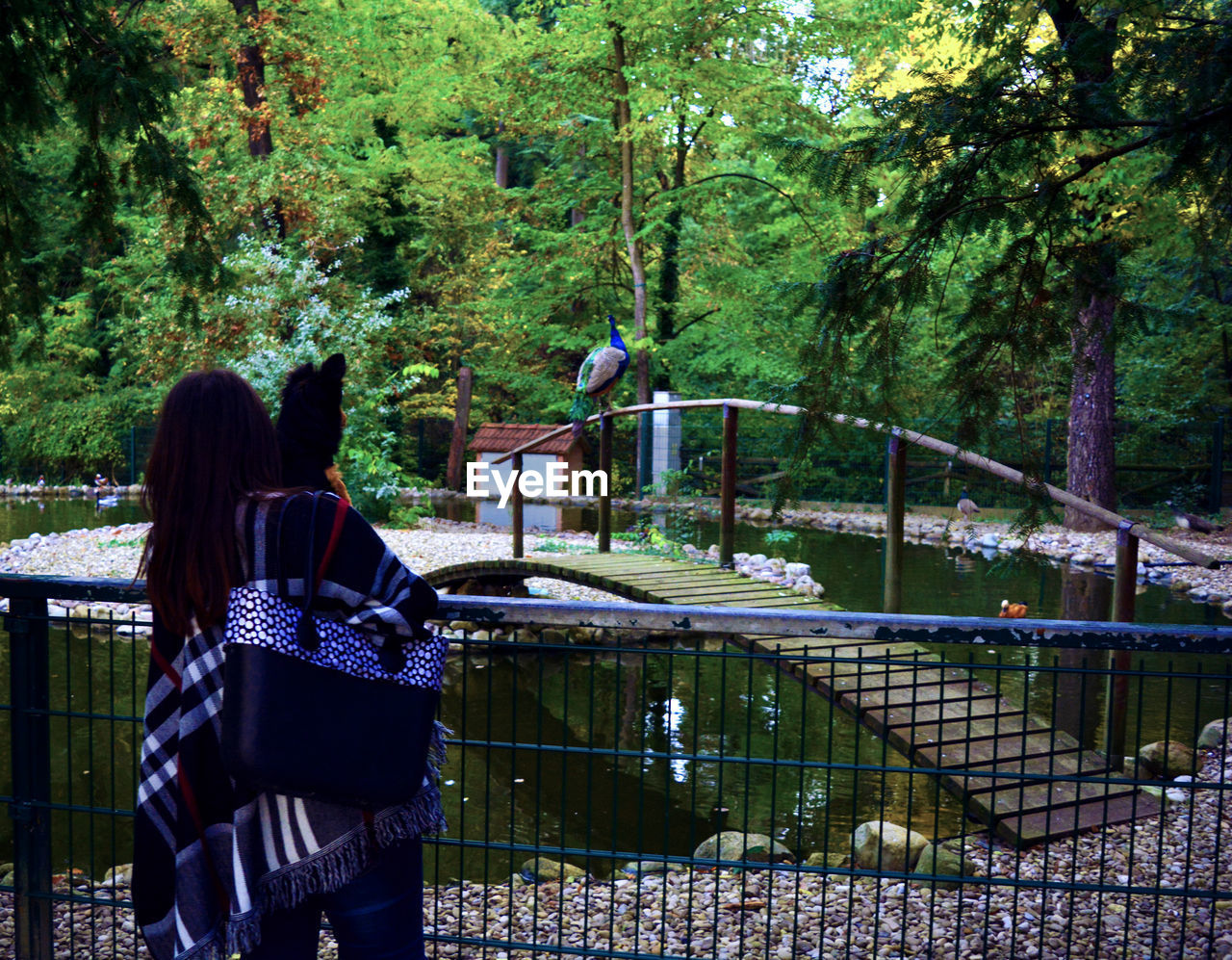 REAR VIEW OF WOMAN BY TREES AGAINST WALL