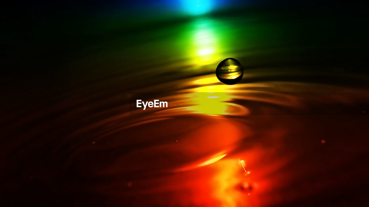 CLOSE-UP OF WATER DROP ON ILLUMINATED LIGHT