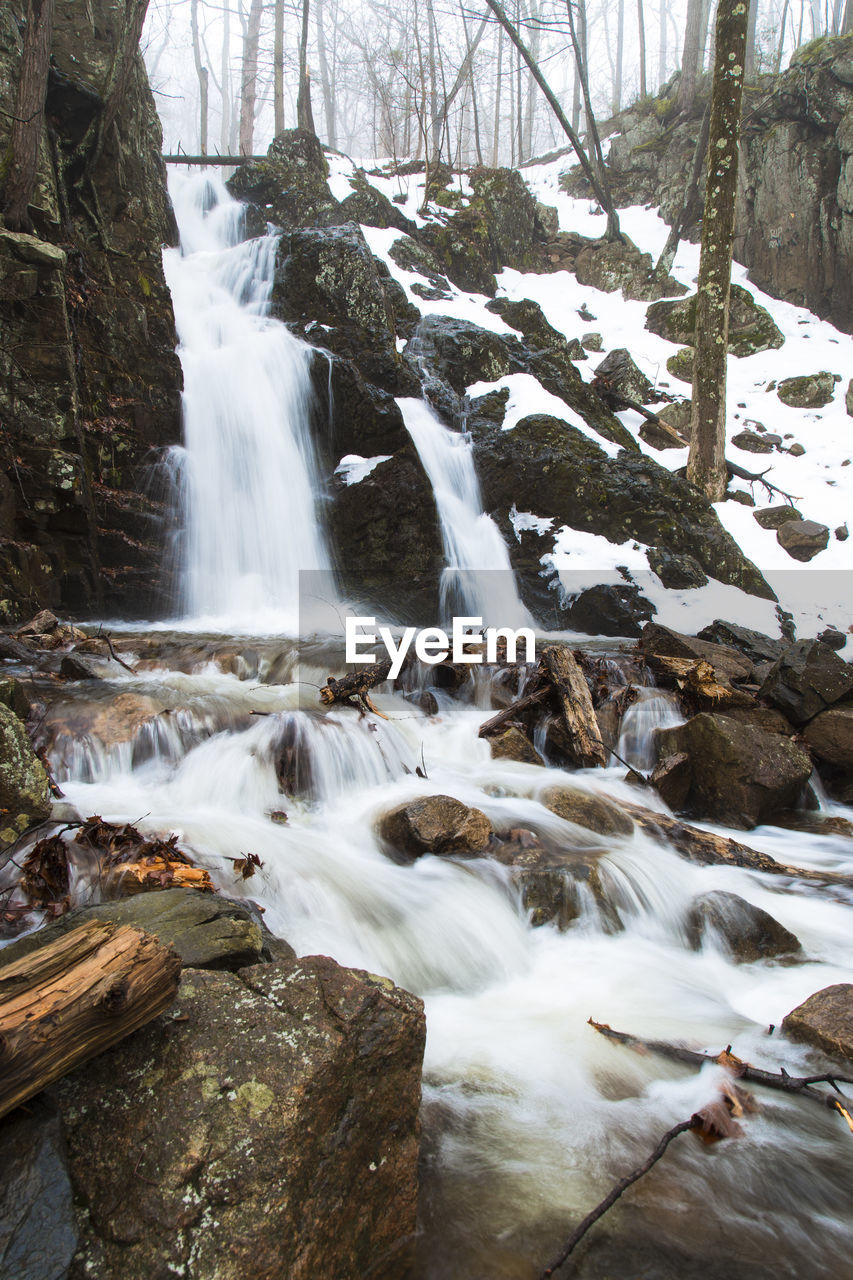 SCENIC VIEW OF WATERFALL AGAINST TREES IN WINTER