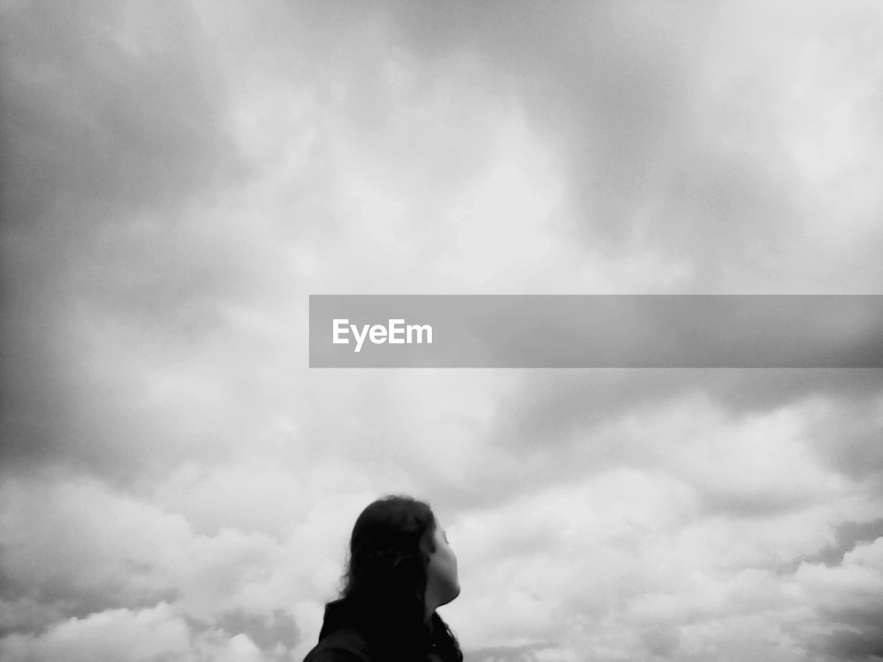 LOW ANGLE VIEW OF TWO PEOPLE STANDING ON CLOUDY DAY