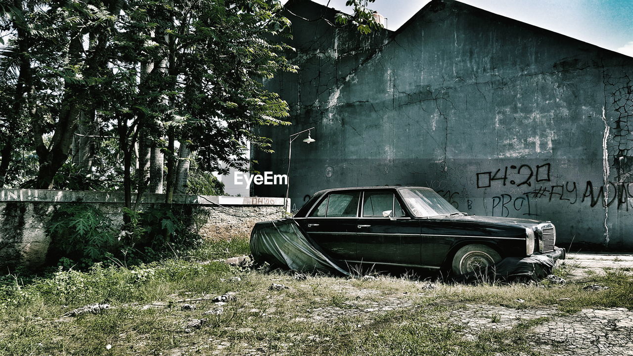 Abandoned vintage car by house