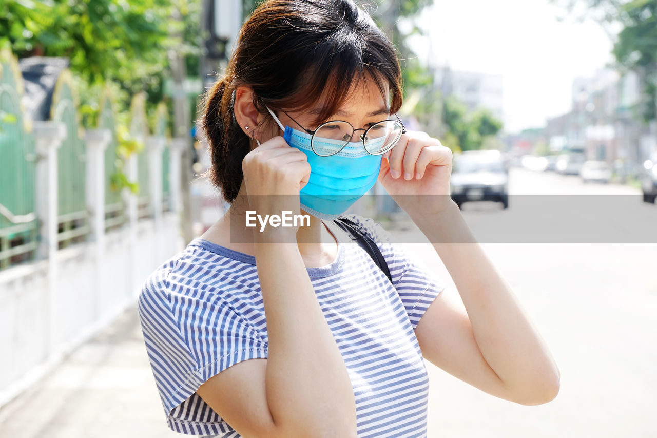 Woman with mask standing in city outdoors