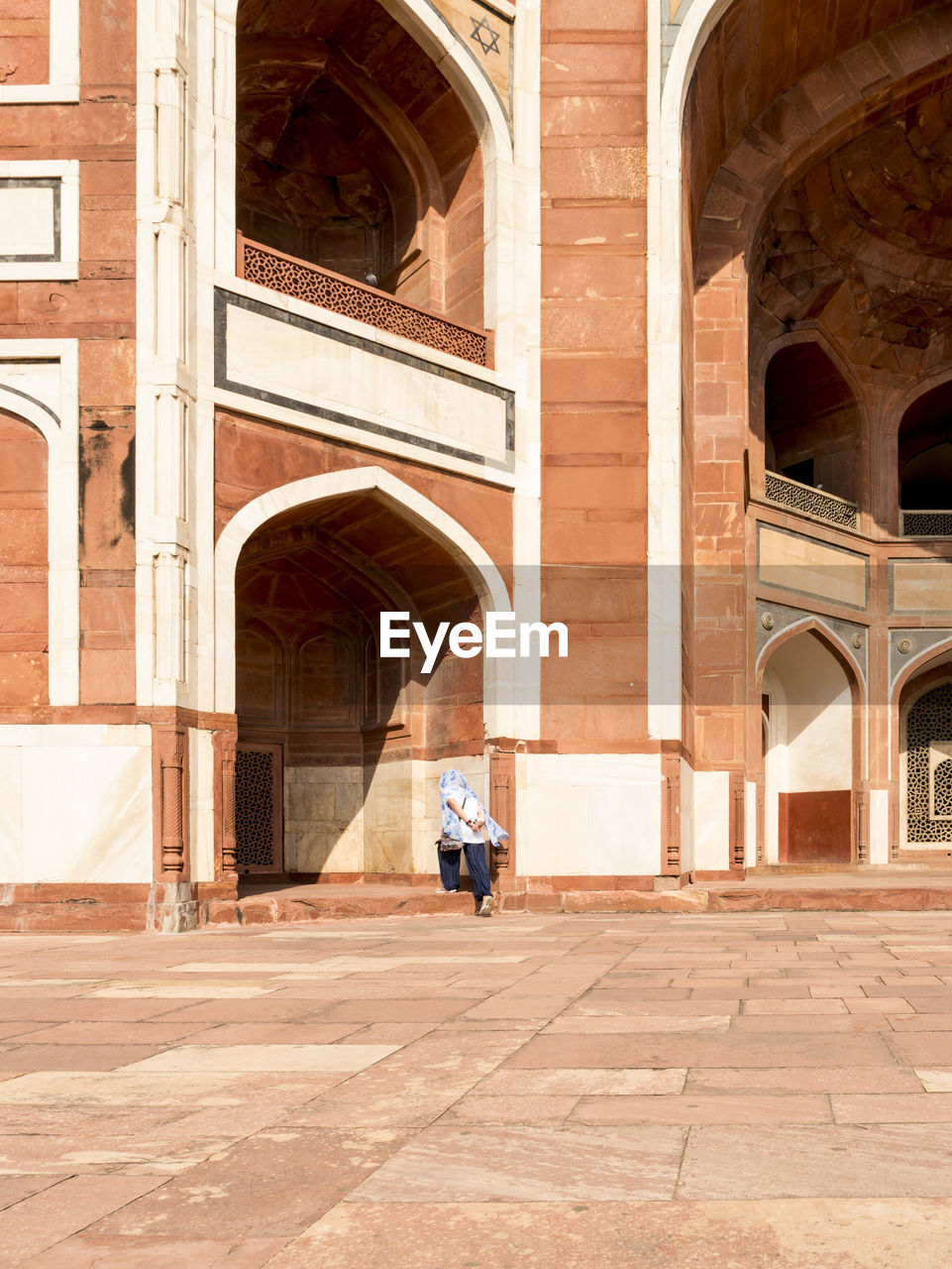 Rear view of woman walking towards historical building during sunny day