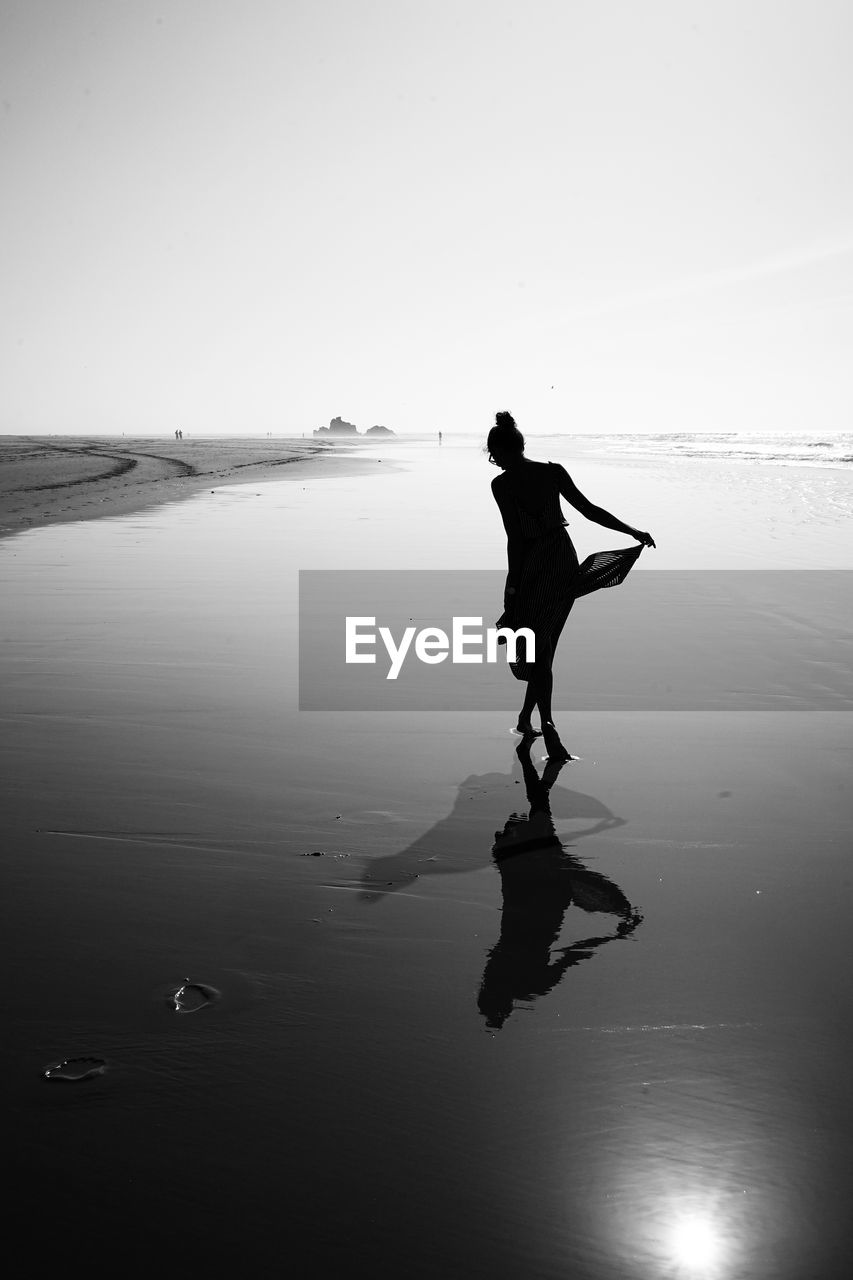 Silhouette woman wading in sea against sky