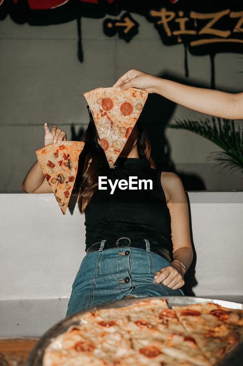 Midsection of woman holding pizza on table