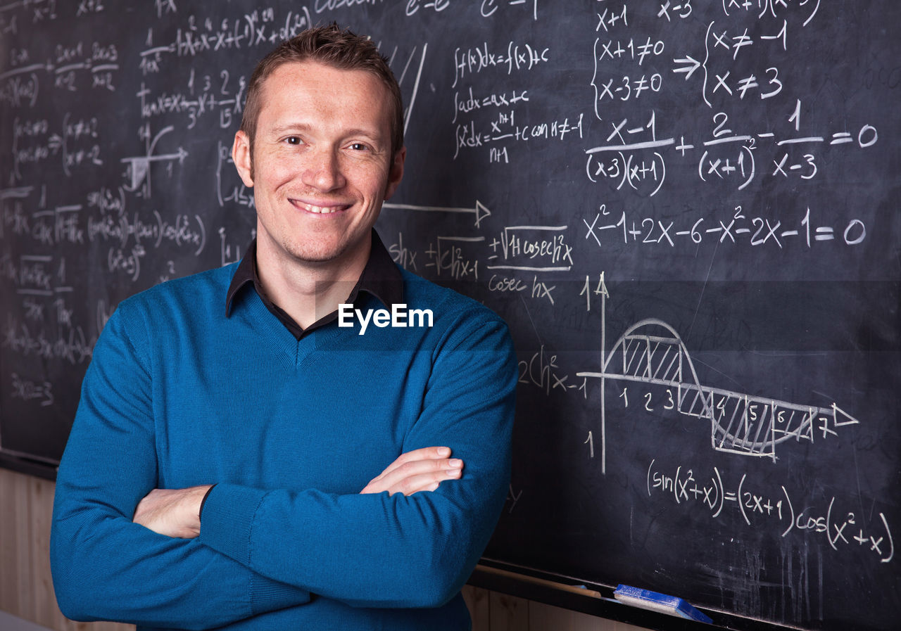 Portrait of smiling man against blackboard