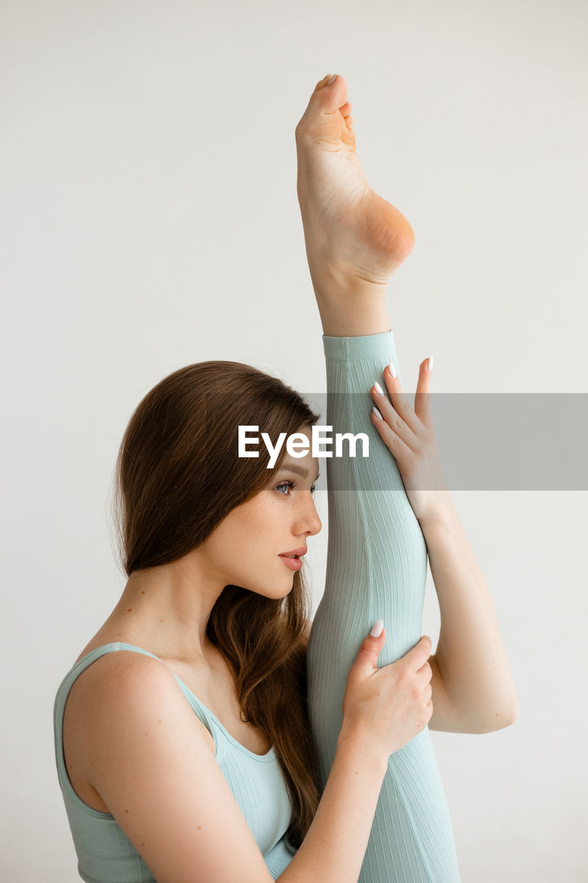 side view of woman with arms crossed against white background