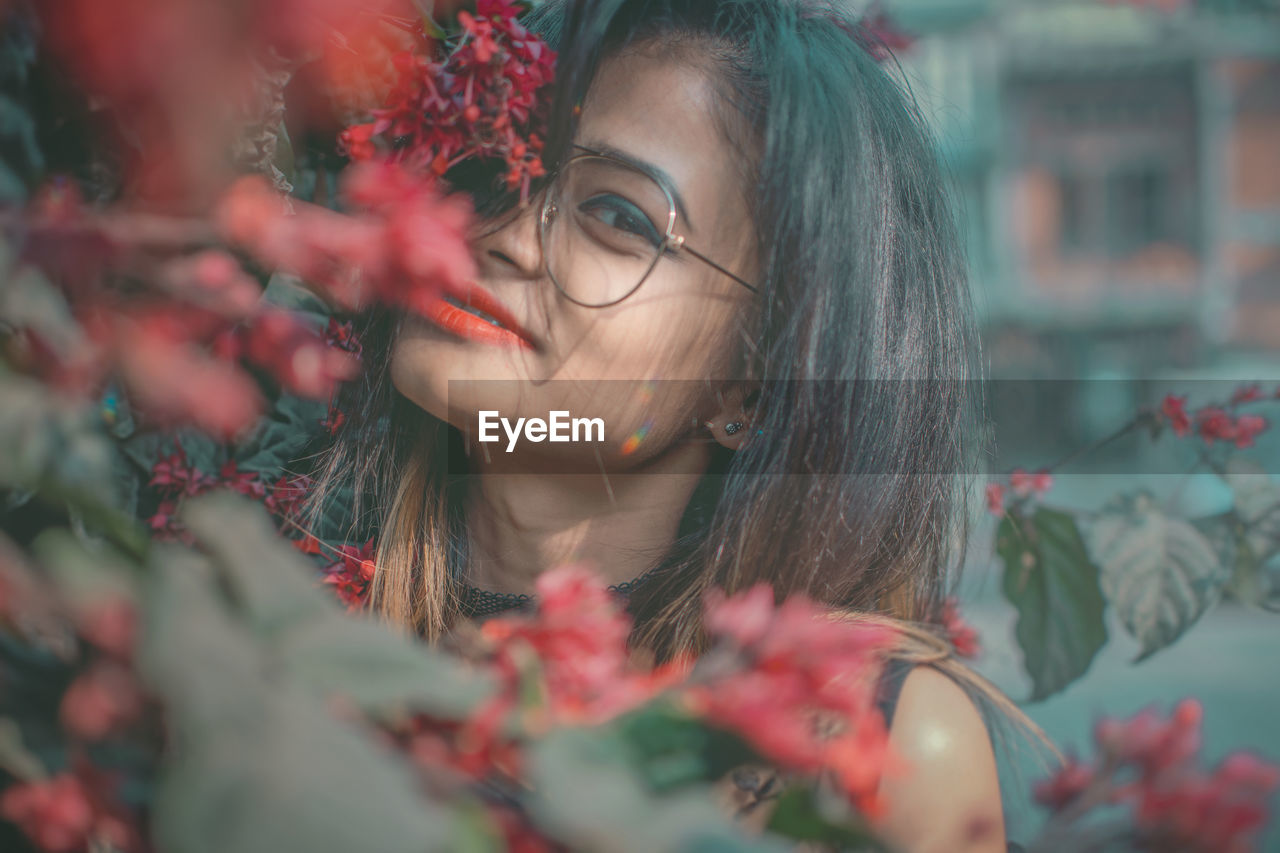 CLOSE-UP OF BEAUTIFUL YOUNG WOMAN WITH FLOWERS IN PARK