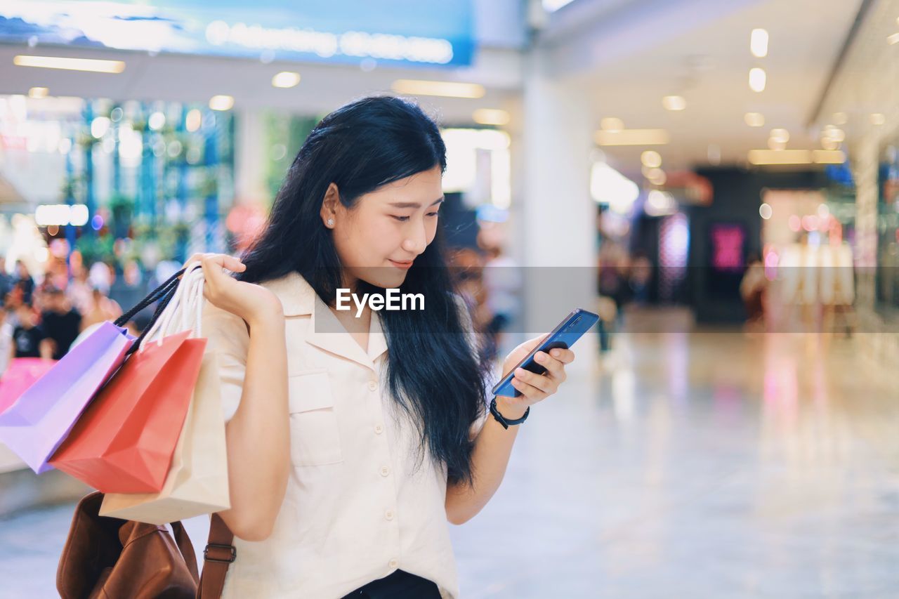 Woman using mobile phone in shopping mall