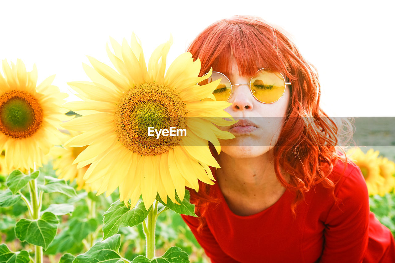 Close-up of beautiful woman wearing sunglasses by sunflower