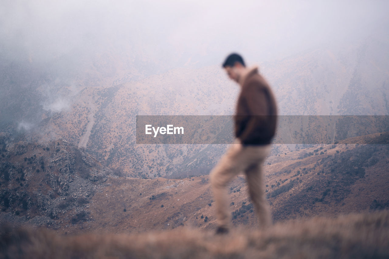 Rear view of man standing on mountain against sky