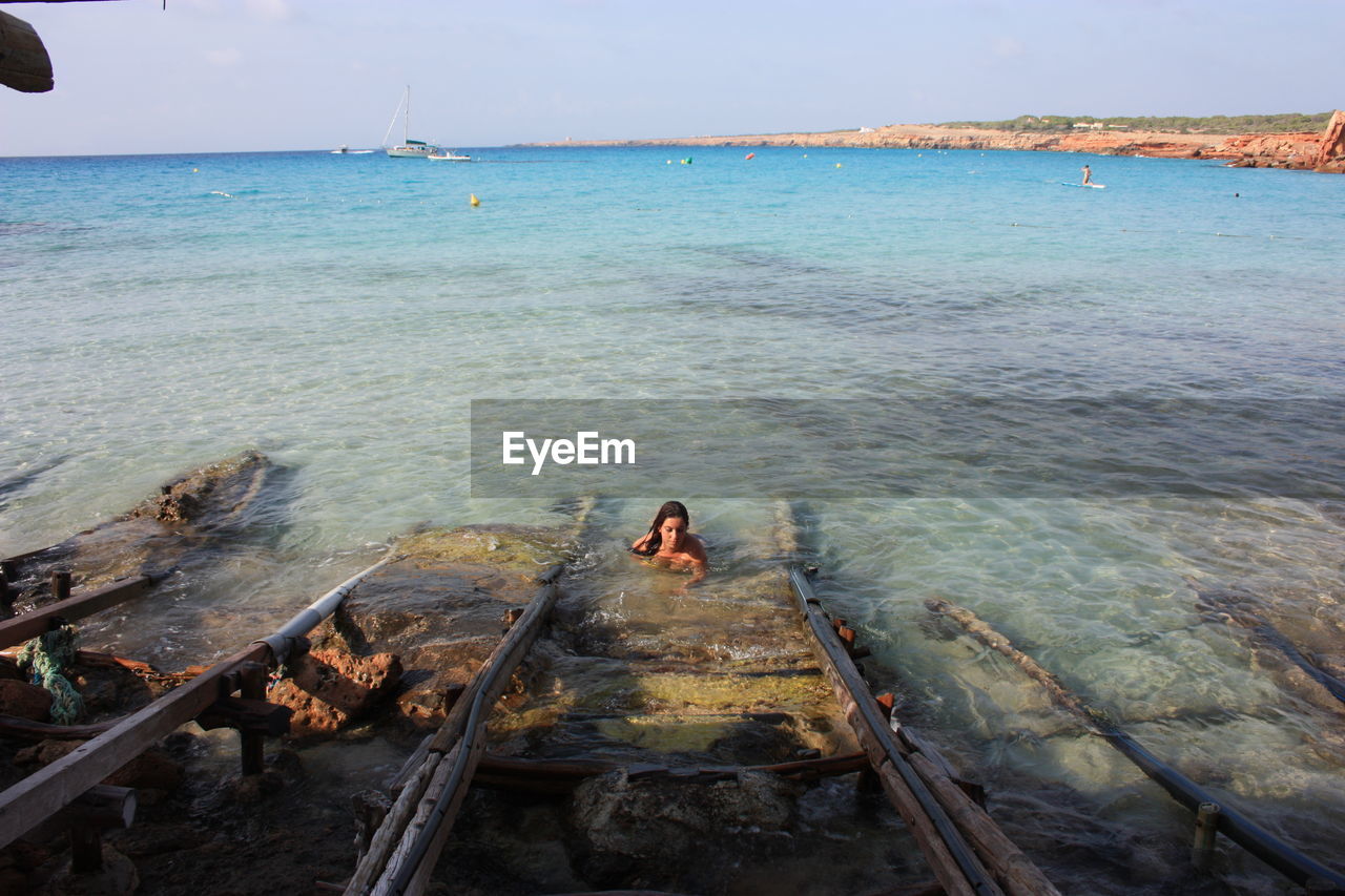 REAR VIEW OF WOMAN LOOKING AT SEA