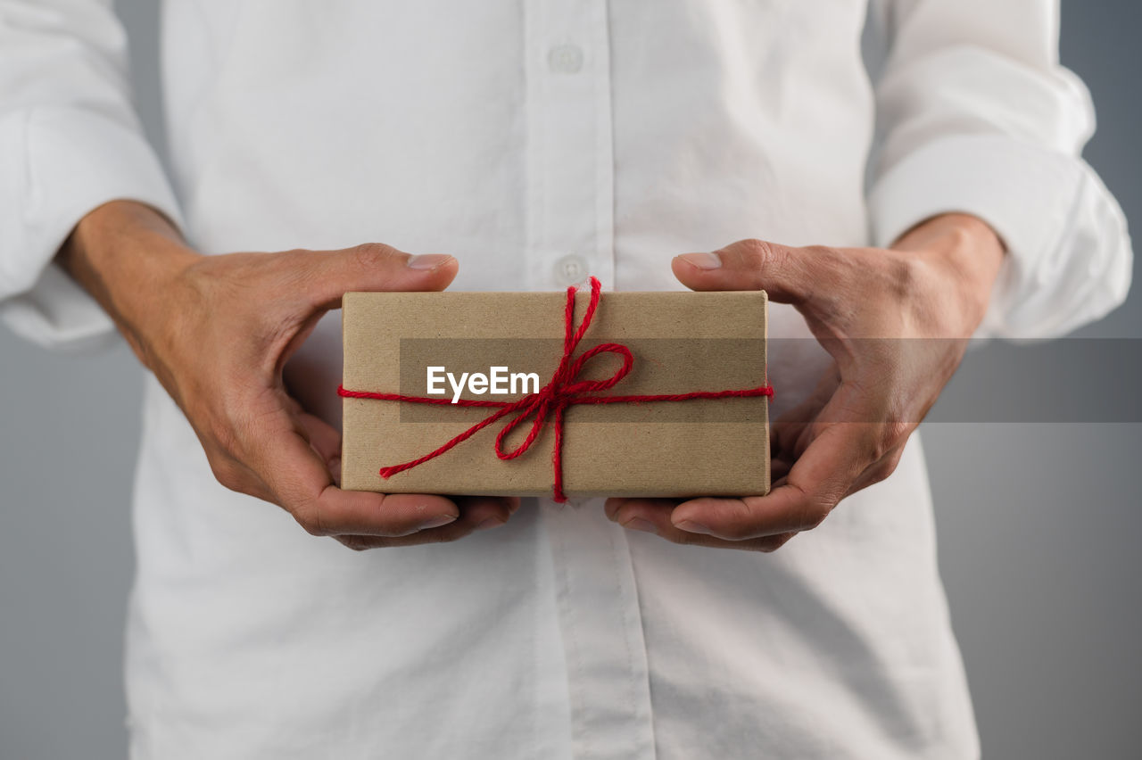 MIDSECTION OF A MAN HOLDING A BOX