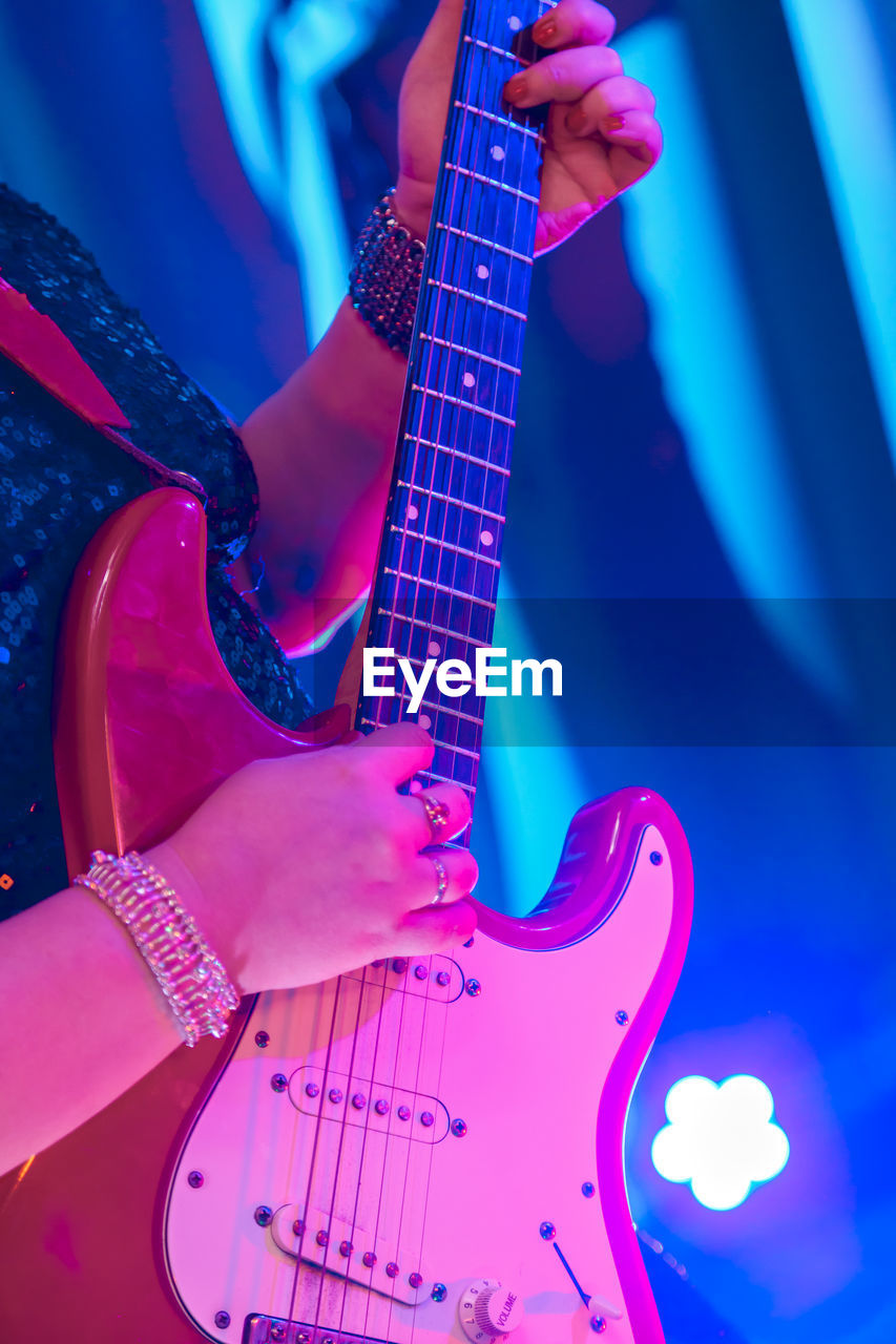 Midsection of woman playing guitar