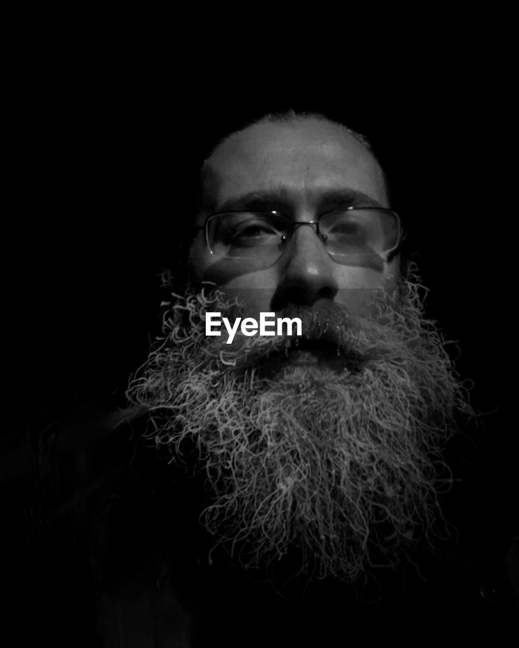 Portrait of man with beard against black background