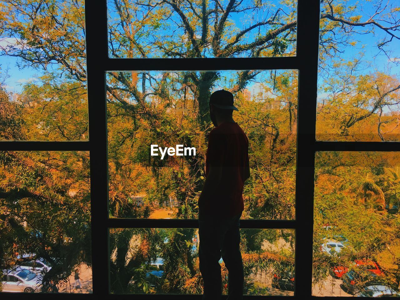REAR VIEW OF PERSON STANDING AGAINST WINDOW
