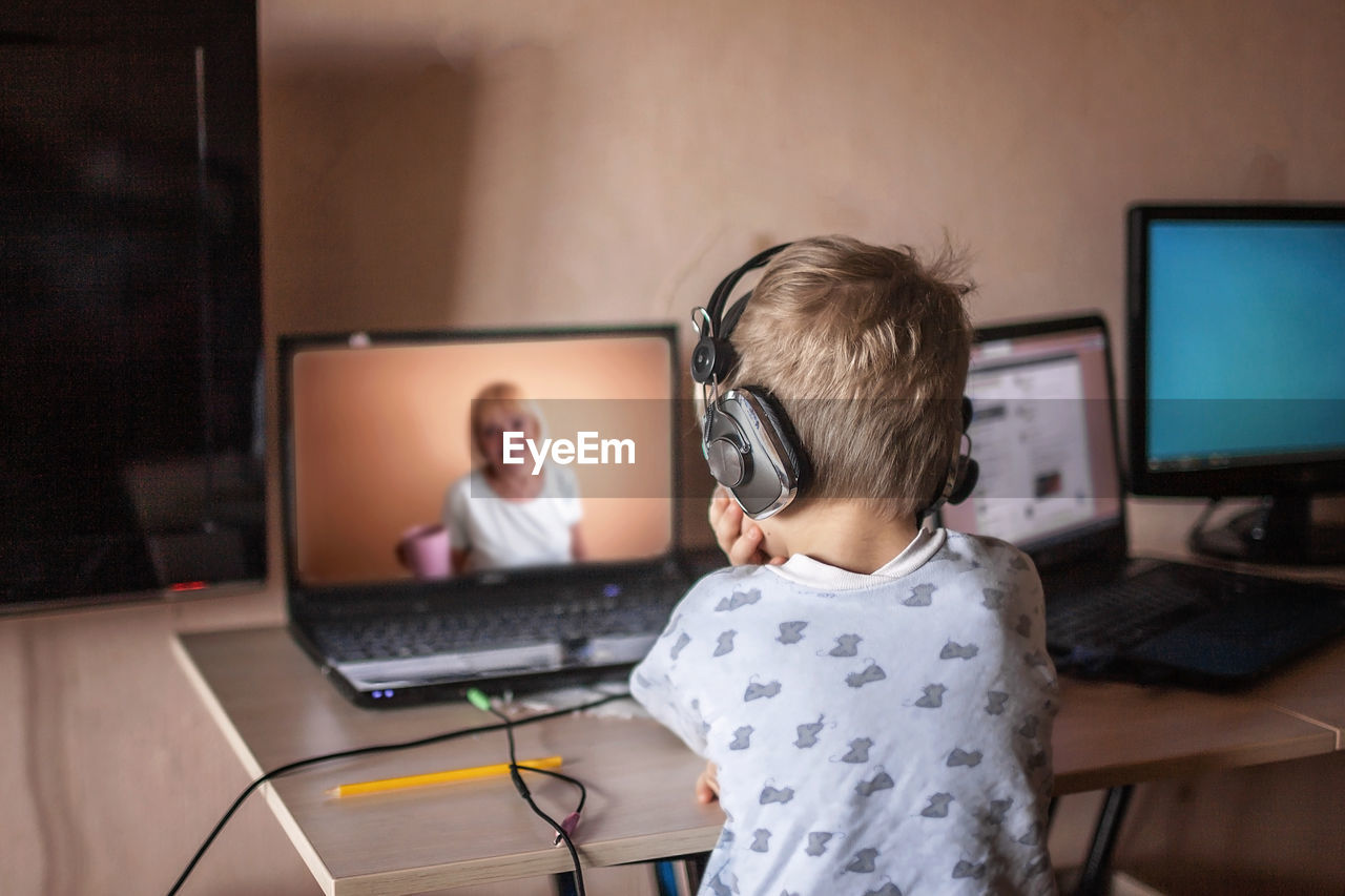 Cute boy talking with his grandmother within video chat on laptop, digital self-isolation