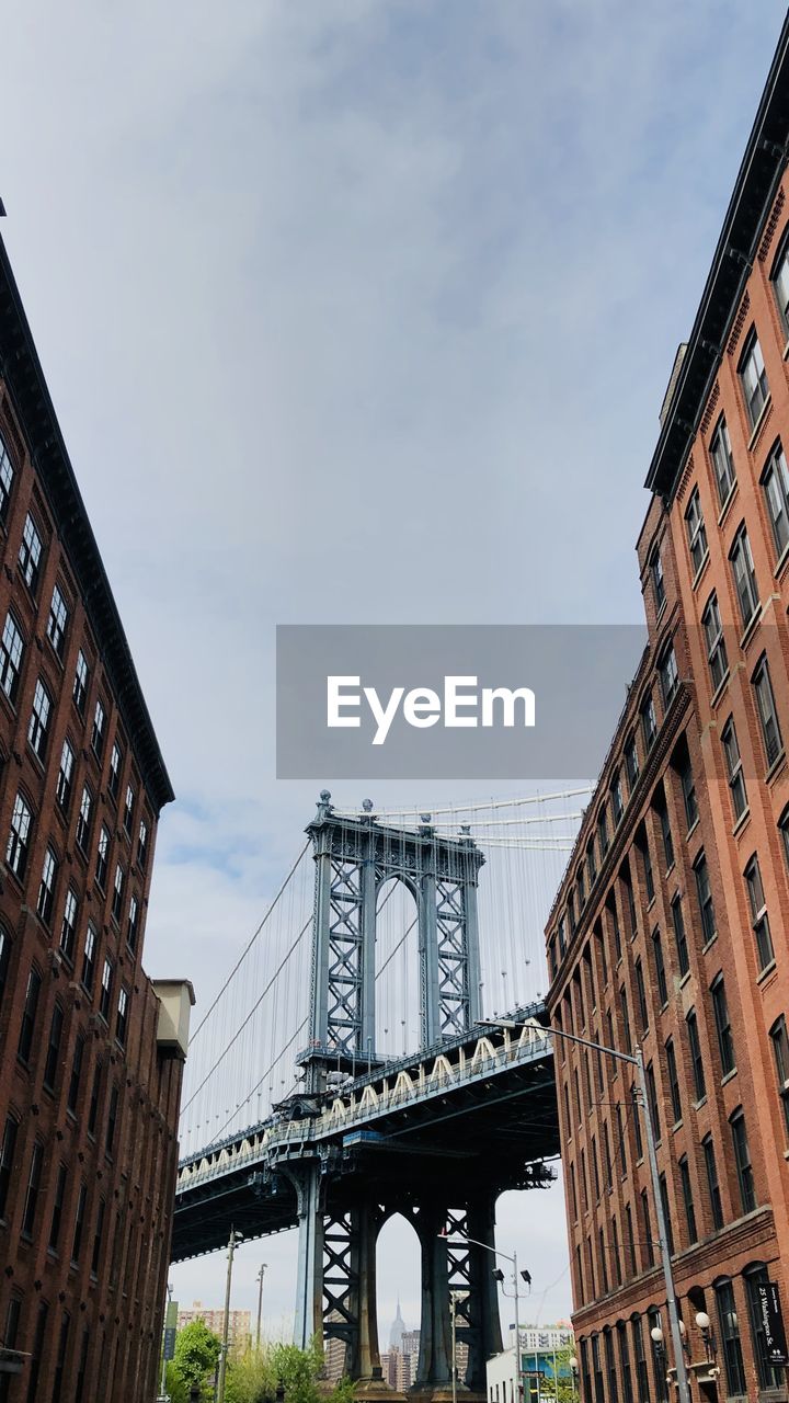 Low angle view of bridge and buildings against sky