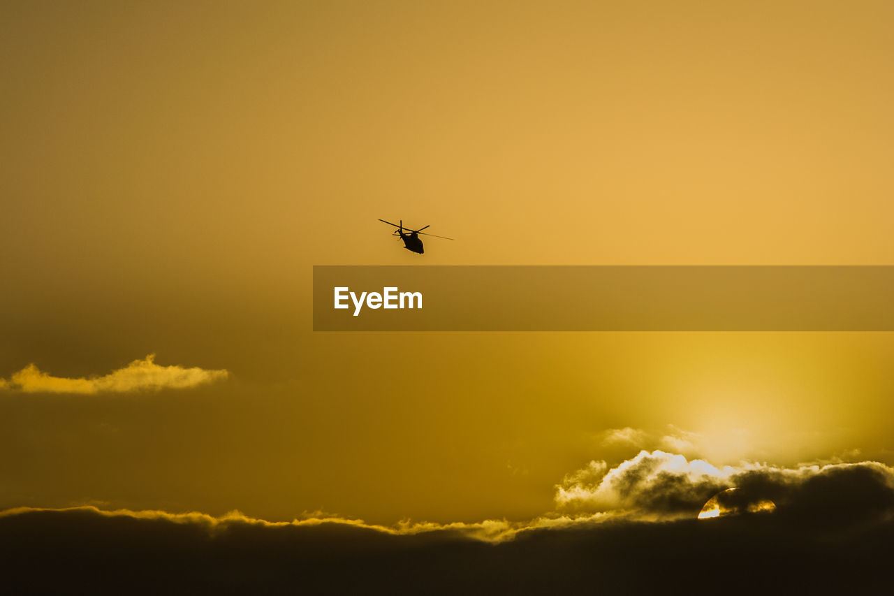 SILHOUETTE OF HELICOPTER FLYING AGAINST SKY