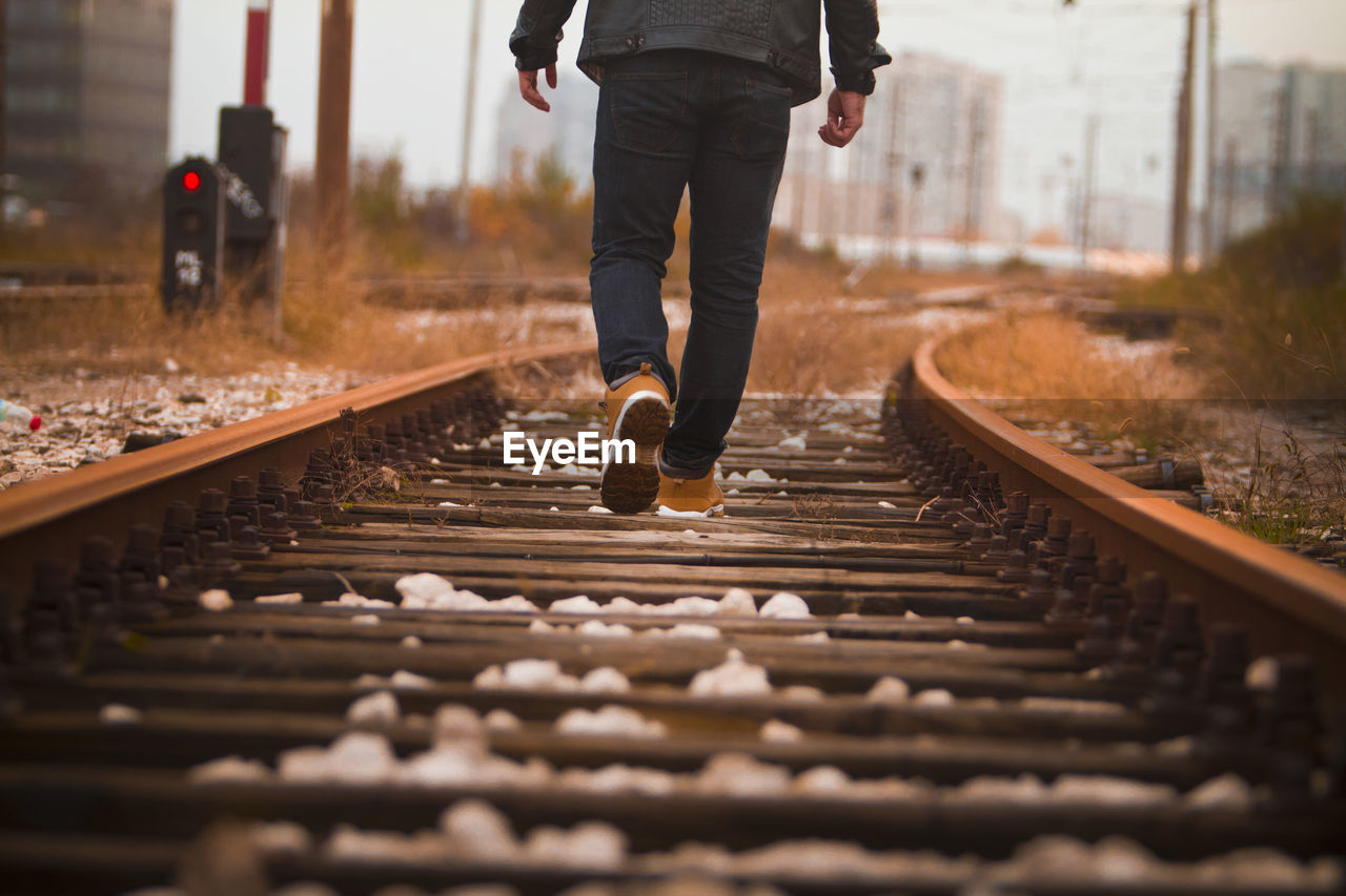 Low section of man walking on railroad track